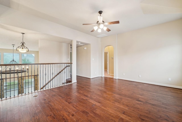 spare room with dark hardwood / wood-style flooring and ceiling fan with notable chandelier