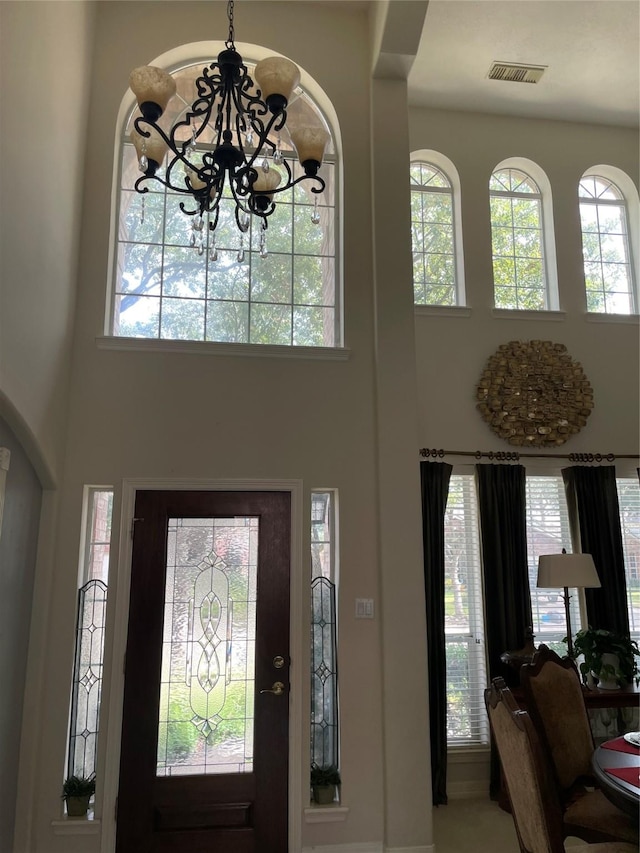 entryway featuring a towering ceiling and a notable chandelier