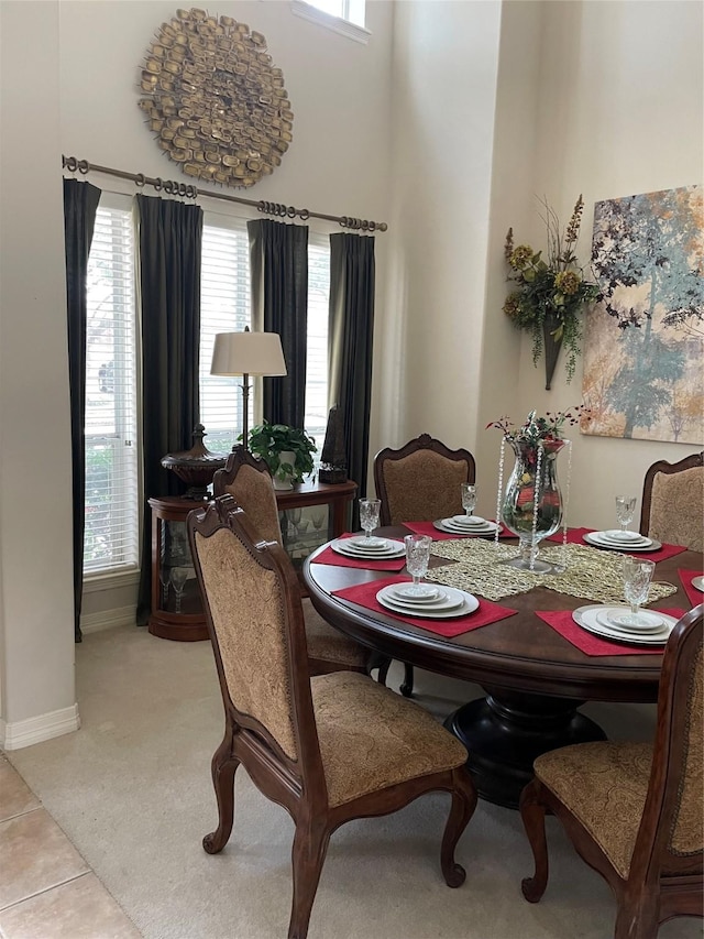 dining room with a towering ceiling, light colored carpet, and plenty of natural light