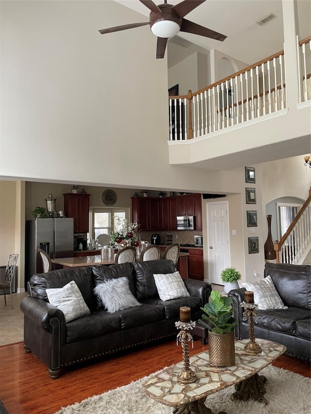 living room with ceiling fan, dark hardwood / wood-style flooring, and a towering ceiling