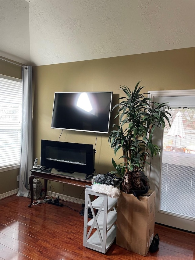 interior space with a textured ceiling, vaulted ceiling, and hardwood / wood-style flooring