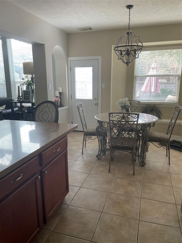 dining space with light tile patterned floors, a textured ceiling, and a notable chandelier