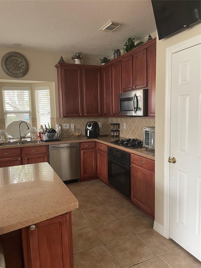 kitchen featuring light stone counters, sink, stainless steel appliances, and tile patterned flooring