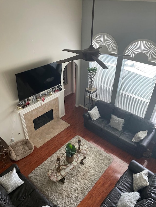 living room with a tile fireplace, dark hardwood / wood-style floors, and ceiling fan