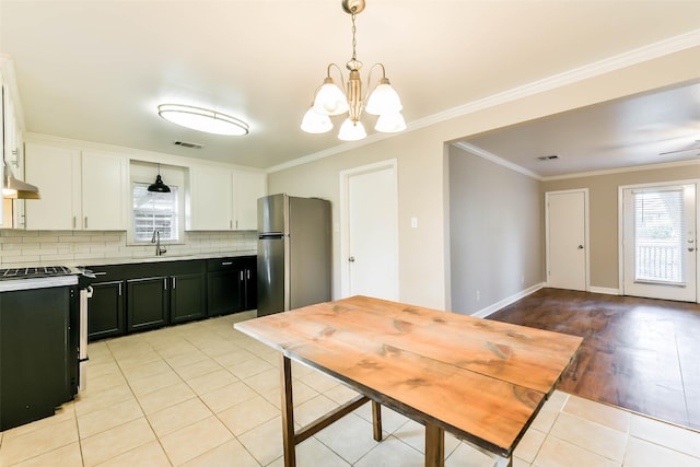 kitchen with stainless steel refrigerator, white cabinets, pendant lighting, and black range