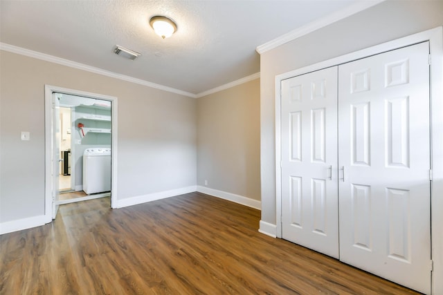 unfurnished bedroom with ornamental molding, a textured ceiling, dark wood-type flooring, washer / clothes dryer, and a closet