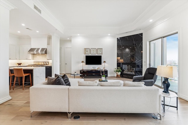 living room featuring a fireplace, light hardwood / wood-style flooring, and crown molding