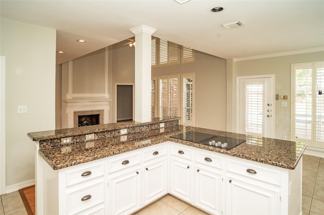 kitchen featuring white cabinets, black electric cooktop, light tile patterned floors, and dark stone counters