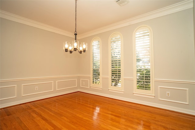 empty room featuring a chandelier, hardwood / wood-style flooring, and ornamental molding