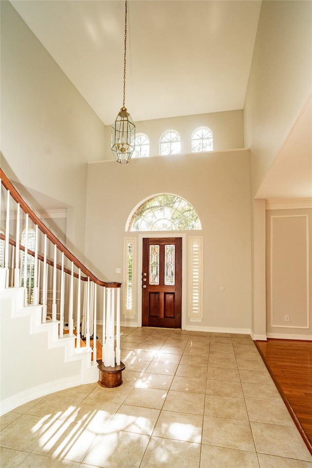 tiled foyer entrance with an inviting chandelier and high vaulted ceiling