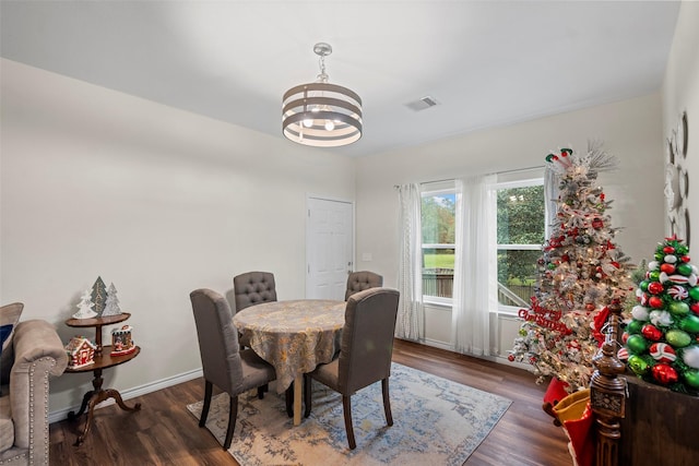 dining space with dark hardwood / wood-style floors and an inviting chandelier