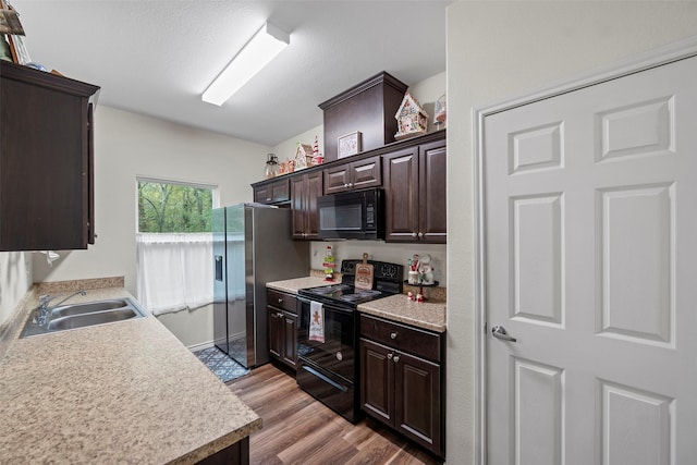 kitchen featuring dark brown cabinets, sink, light hardwood / wood-style floors, and black appliances