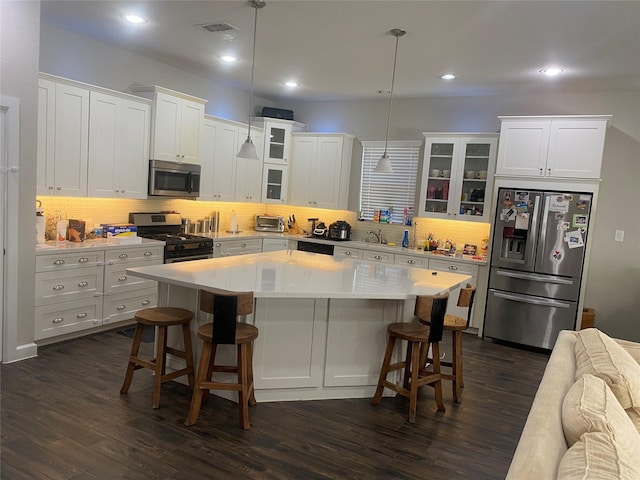 kitchen with a breakfast bar area, dark hardwood / wood-style floors, decorative light fixtures, a kitchen island, and stainless steel appliances