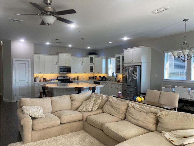 living room featuring hardwood / wood-style floors, ceiling fan with notable chandelier, plenty of natural light, and sink