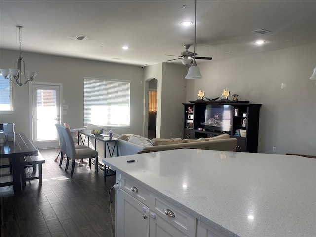 kitchen featuring light stone countertops, ceiling fan with notable chandelier, dark hardwood / wood-style floors, white cabinetry, and hanging light fixtures