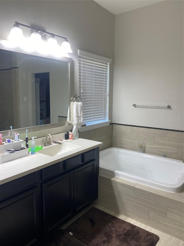 bathroom featuring a relaxing tiled tub and vanity