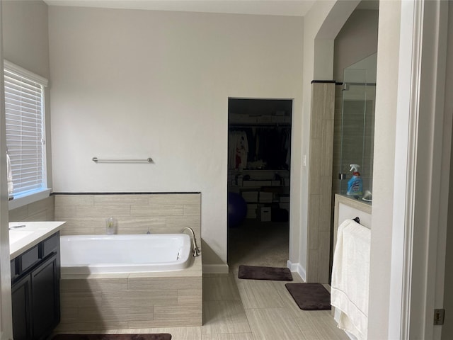 bathroom featuring vanity, tiled bath, tile patterned floors, and a healthy amount of sunlight