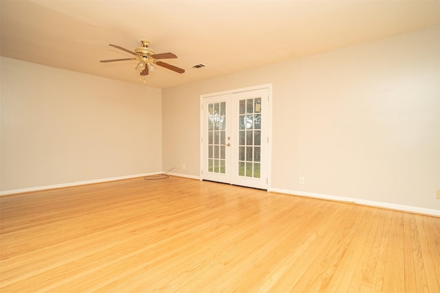 empty room with ceiling fan, light wood-type flooring, and french doors