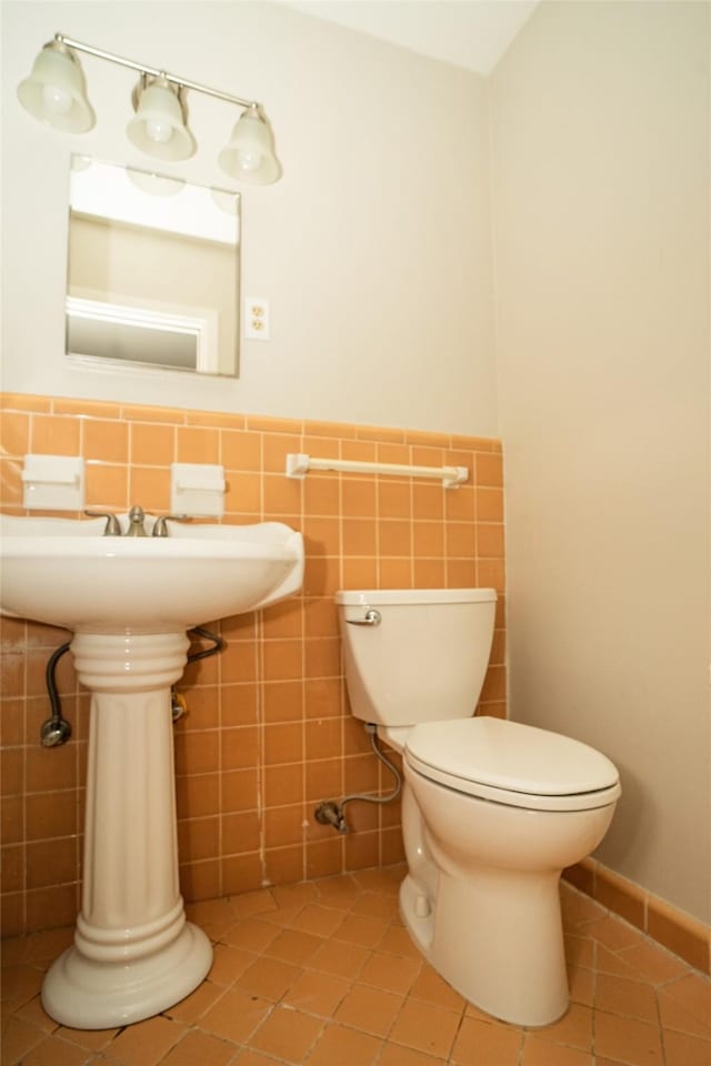 bathroom featuring tile patterned floors, toilet, and tile walls