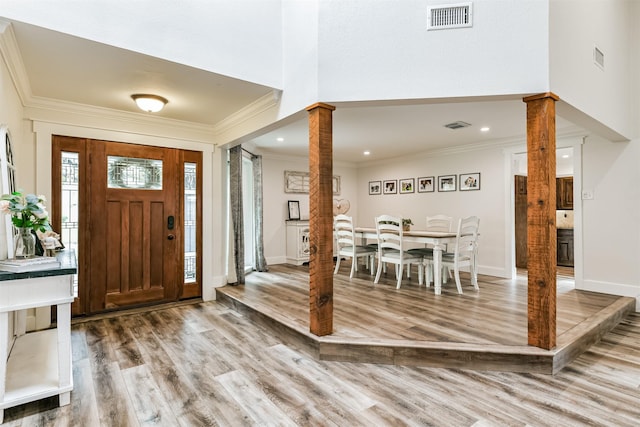 entrance foyer with hardwood / wood-style floors, decorative columns, and ornamental molding