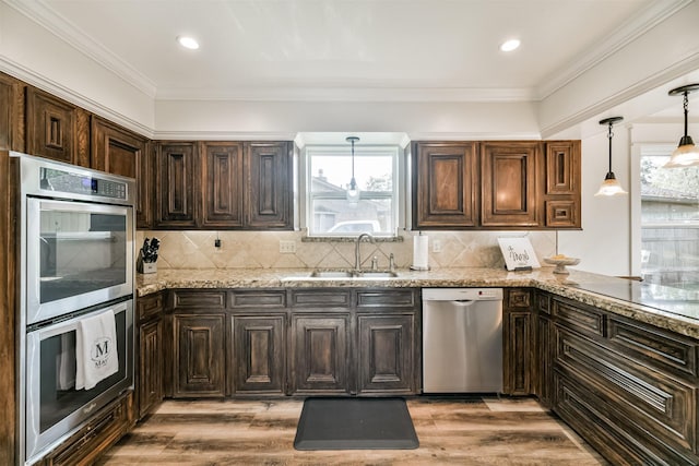 kitchen with backsplash, sink, appliances with stainless steel finishes, light hardwood / wood-style floors, and light stone counters