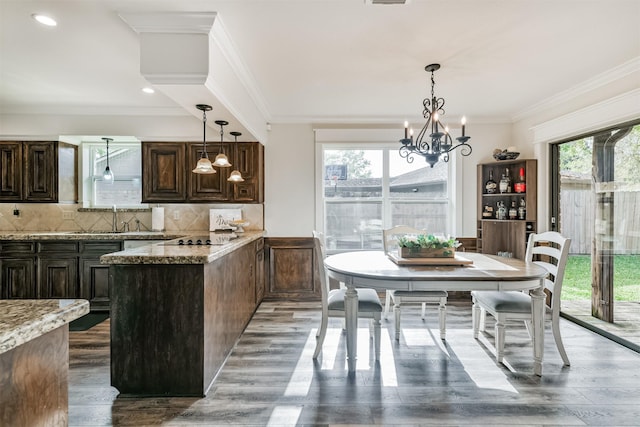 kitchen with backsplash, a notable chandelier, light stone countertops, and hanging light fixtures