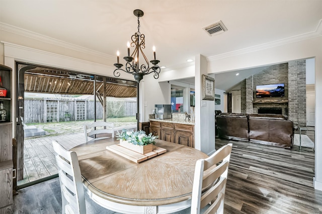 dining room featuring a notable chandelier, dark hardwood / wood-style floors, a fireplace, and vaulted ceiling