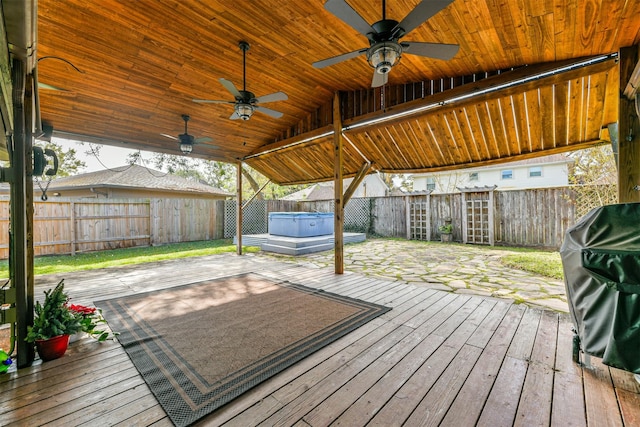 wooden deck with grilling area, a hot tub, ceiling fan, and a patio area