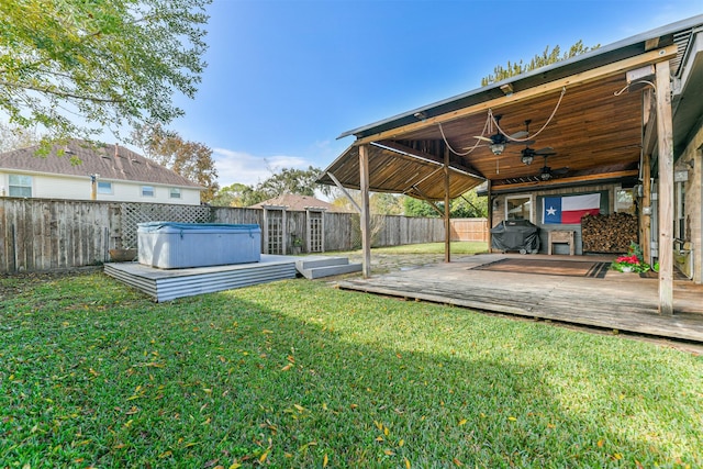 view of yard with ceiling fan, a deck, and a hot tub