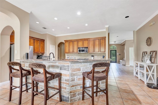 kitchen with decorative backsplash, kitchen peninsula, a breakfast bar area, and ornamental molding