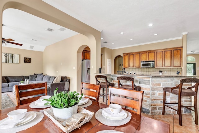 dining space with ceiling fan, crown molding, and light tile patterned floors