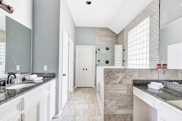 bathroom with tile walls, vanity, vaulted ceiling, and tiled shower