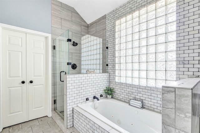 bathroom featuring tile patterned flooring, shower with separate bathtub, vaulted ceiling, and tile walls