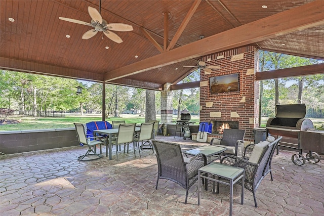 sunroom / solarium featuring lofted ceiling with beams, an outdoor brick fireplace, a wealth of natural light, and ceiling fan