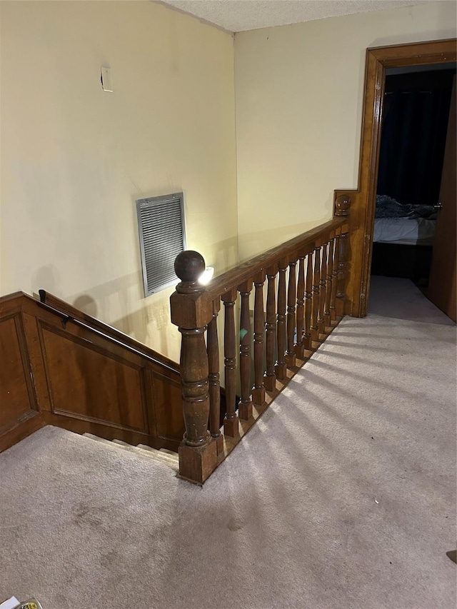 stairway featuring carpet floors and a textured ceiling