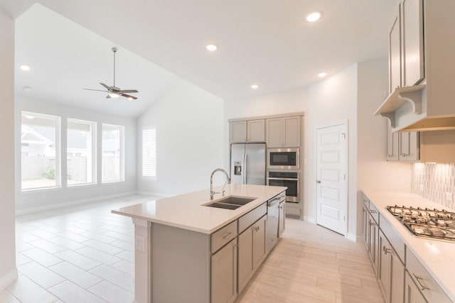 kitchen with appliances with stainless steel finishes, decorative backsplash, sink, a kitchen island with sink, and vaulted ceiling