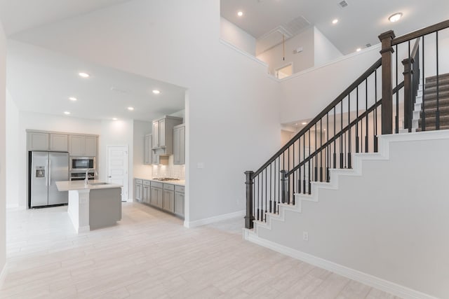 stairs featuring sink, a high ceiling, and hardwood / wood-style floors