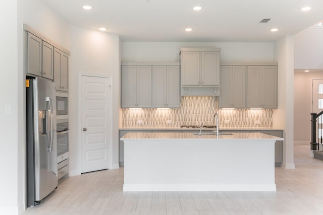 kitchen featuring a center island with sink, stainless steel appliances, and tasteful backsplash