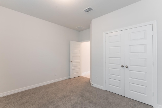 unfurnished bedroom with light colored carpet and a closet