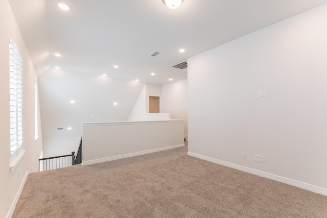 carpeted spare room featuring vaulted ceiling