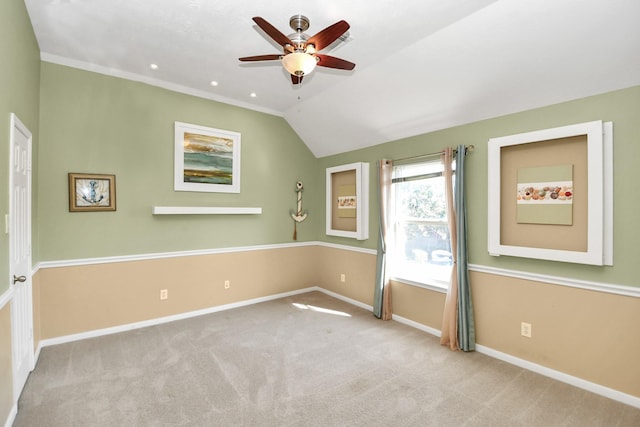 carpeted empty room with ceiling fan, vaulted ceiling, and ornamental molding