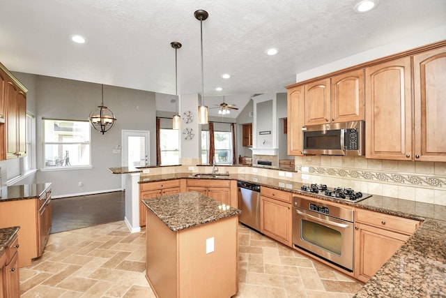 kitchen with ceiling fan with notable chandelier, stainless steel appliances, decorative light fixtures, a kitchen island, and lofted ceiling