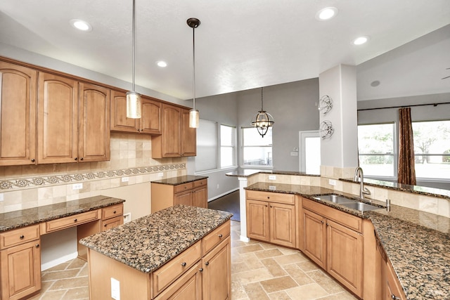 kitchen featuring dark stone countertops, sink, a center island, and decorative light fixtures