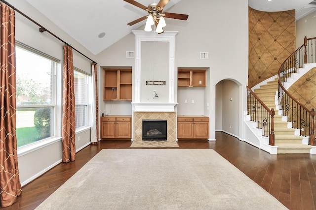 living room with a wealth of natural light, a fireplace, high vaulted ceiling, and dark hardwood / wood-style floors