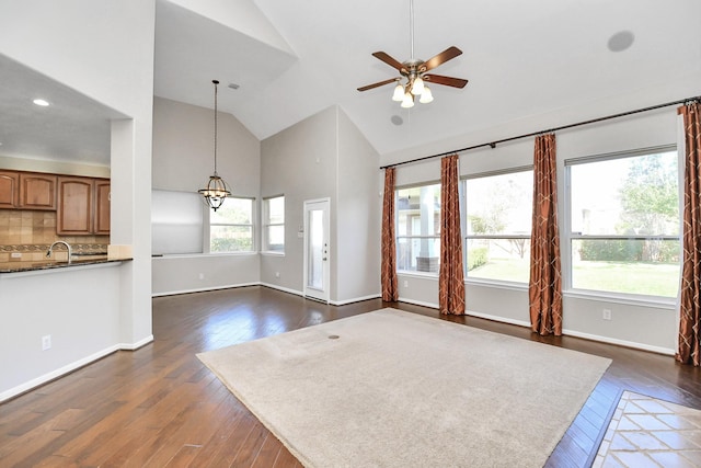 unfurnished living room featuring dark hardwood / wood-style flooring, high vaulted ceiling, ceiling fan, and sink