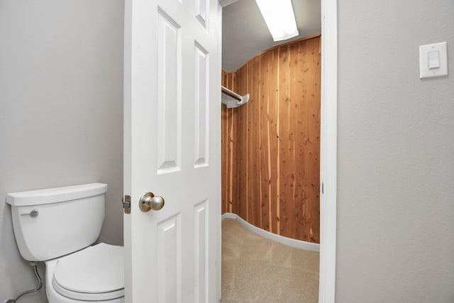 bathroom featuring wooden walls and toilet