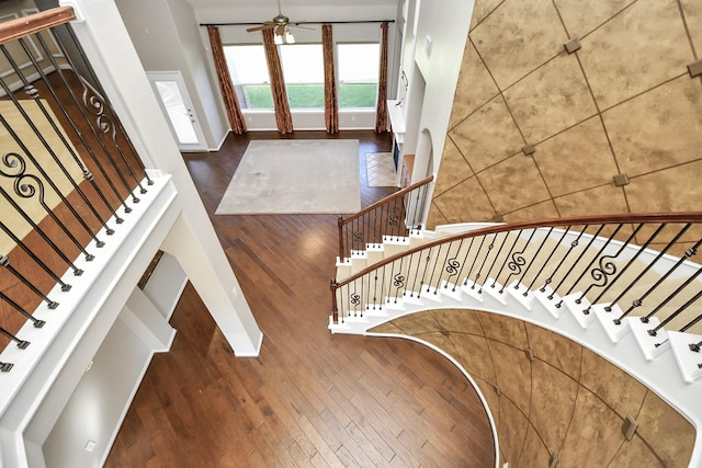 staircase featuring wood-type flooring and ceiling fan