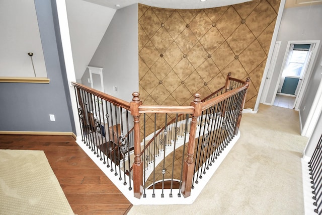 stairway with high vaulted ceiling, tile walls, and hardwood / wood-style flooring