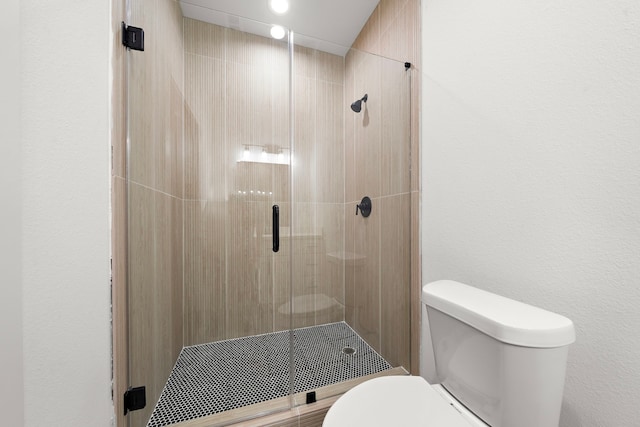 bathroom with a shower with door and toilet