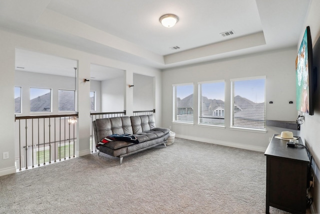 living area featuring a tray ceiling and carpet